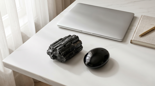 Raw Black Tourmaline and polished Black Obsidian crystals next to a modern laptop for digital detox and EMF protection.