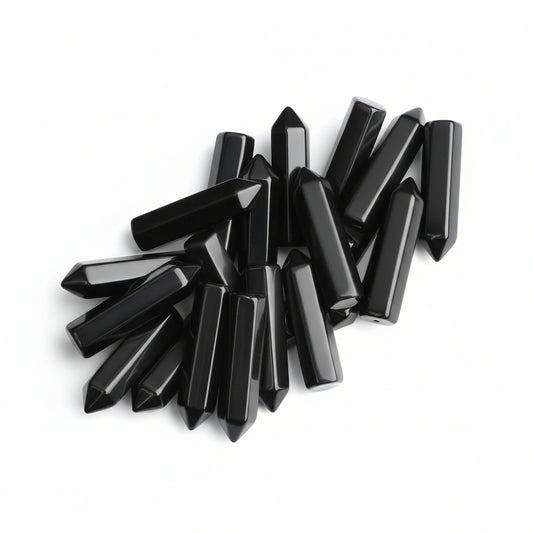 20 pieces of polished black obsidian crystal wands held in a hand, showing hexagonal points for healing and meditation.